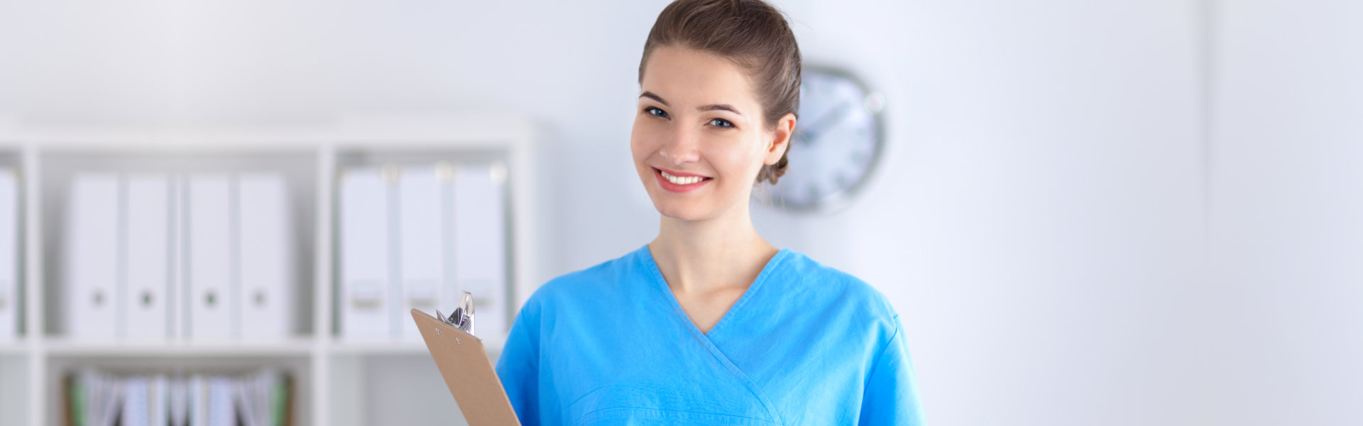 young caregiver smiling while holding a clipboard