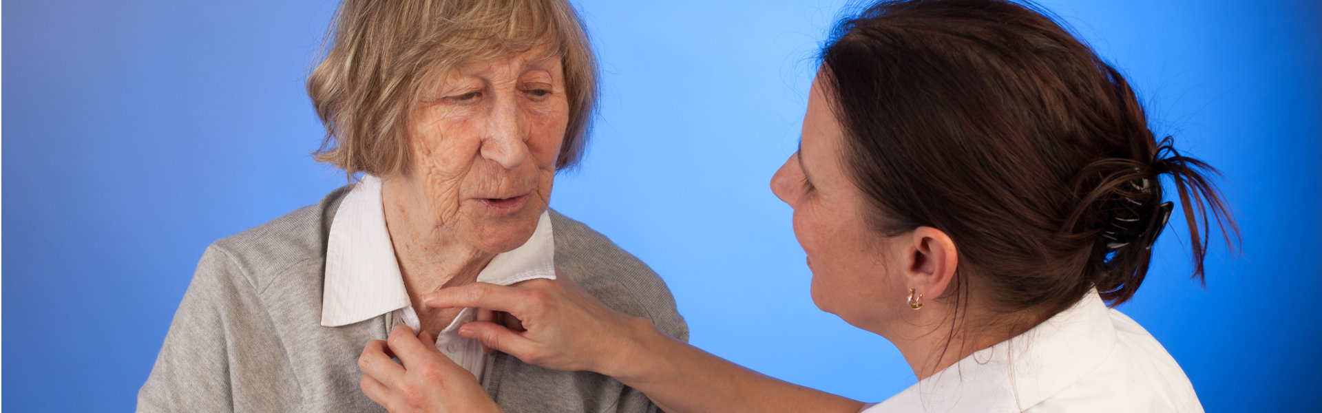 carer helps elderly woman with dressing